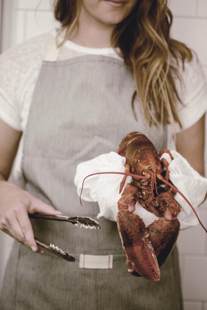 woman wearing aprons holding a lobster